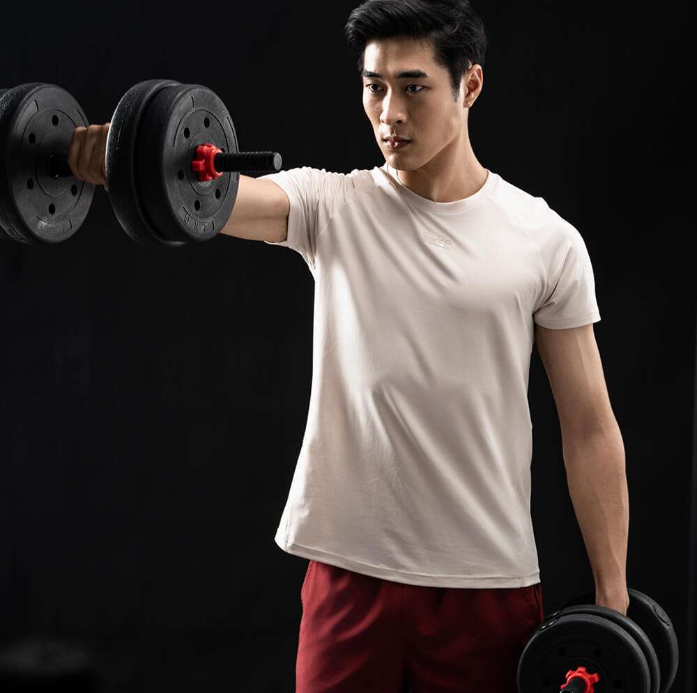 Người mẫu nam mặc áo thun gym Powerfit màu be khi tập tạ tay