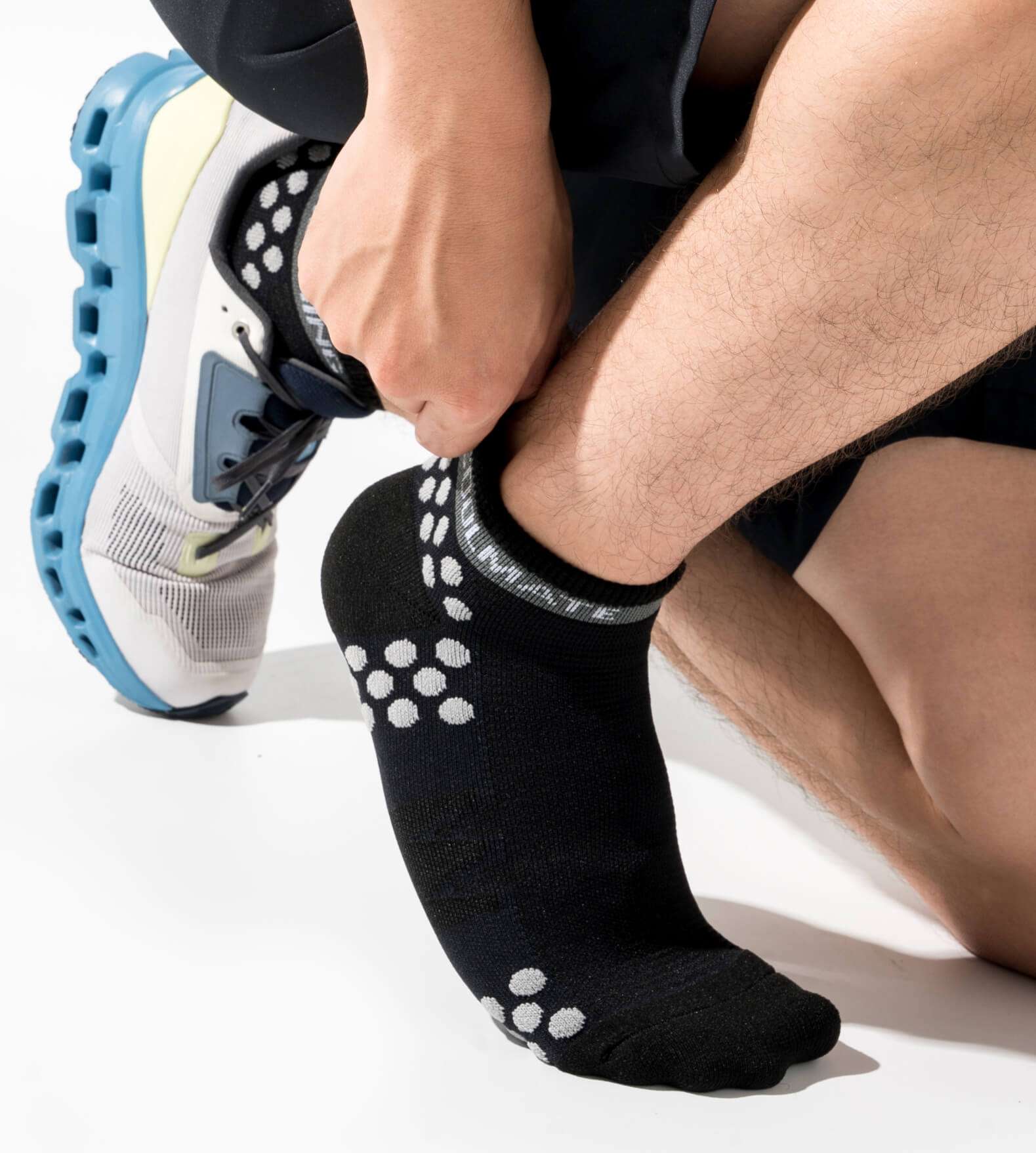 Người mẫu xỏ giày thể thao cùng tất chạy bộ Professional màu đen.